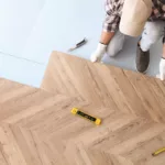 Worker installing laminate wooden floors as a tenant improvement, above view