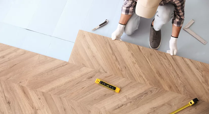 Worker installing laminate wooden floors as a tenant improvement, above view