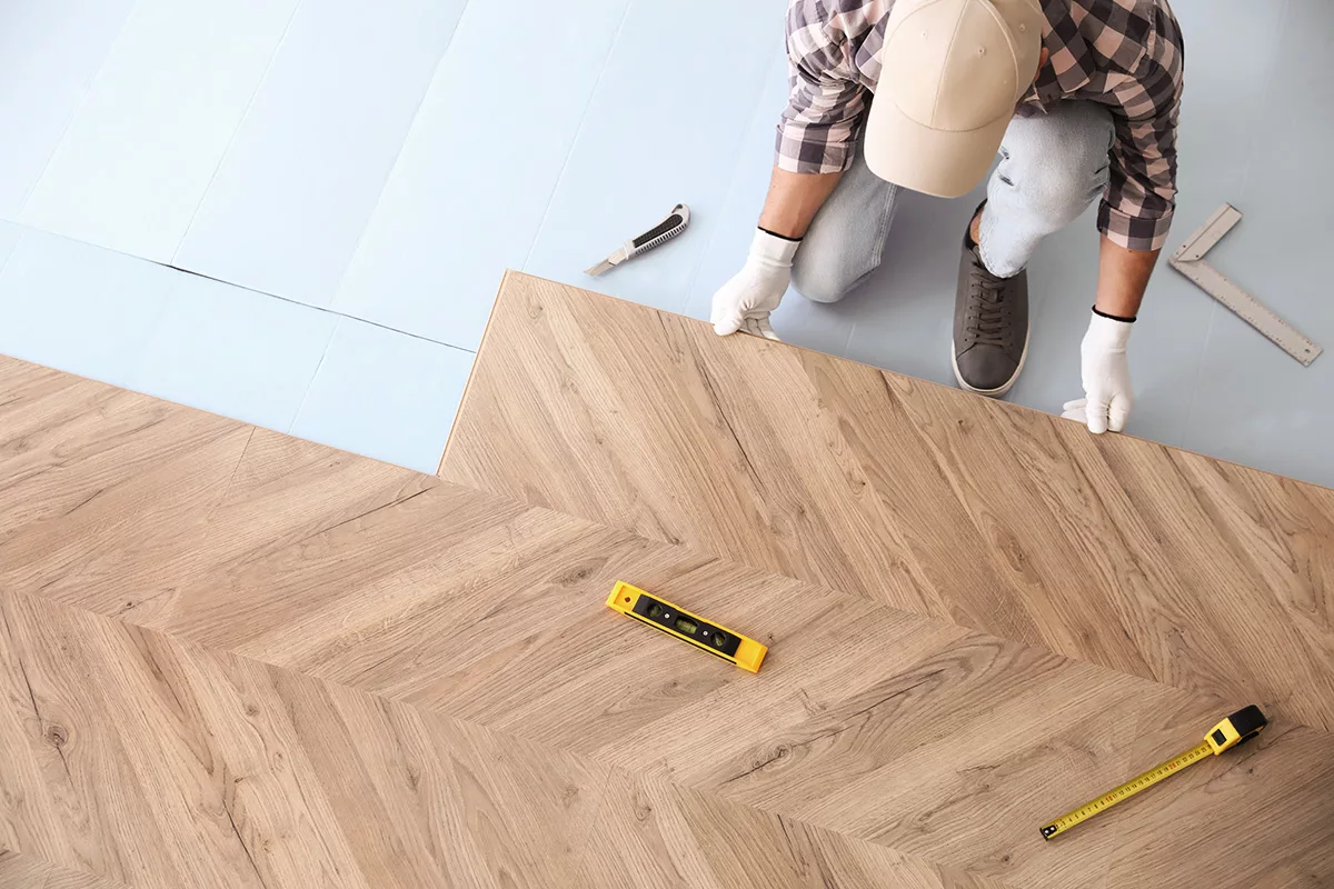 Worker installing laminate wooden floors as a tenant improvement, above view