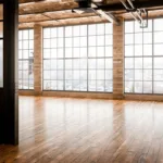 The interior of a modern commercial building after a commercial remodeling project, with brick walls, large windows, and hardwood floors