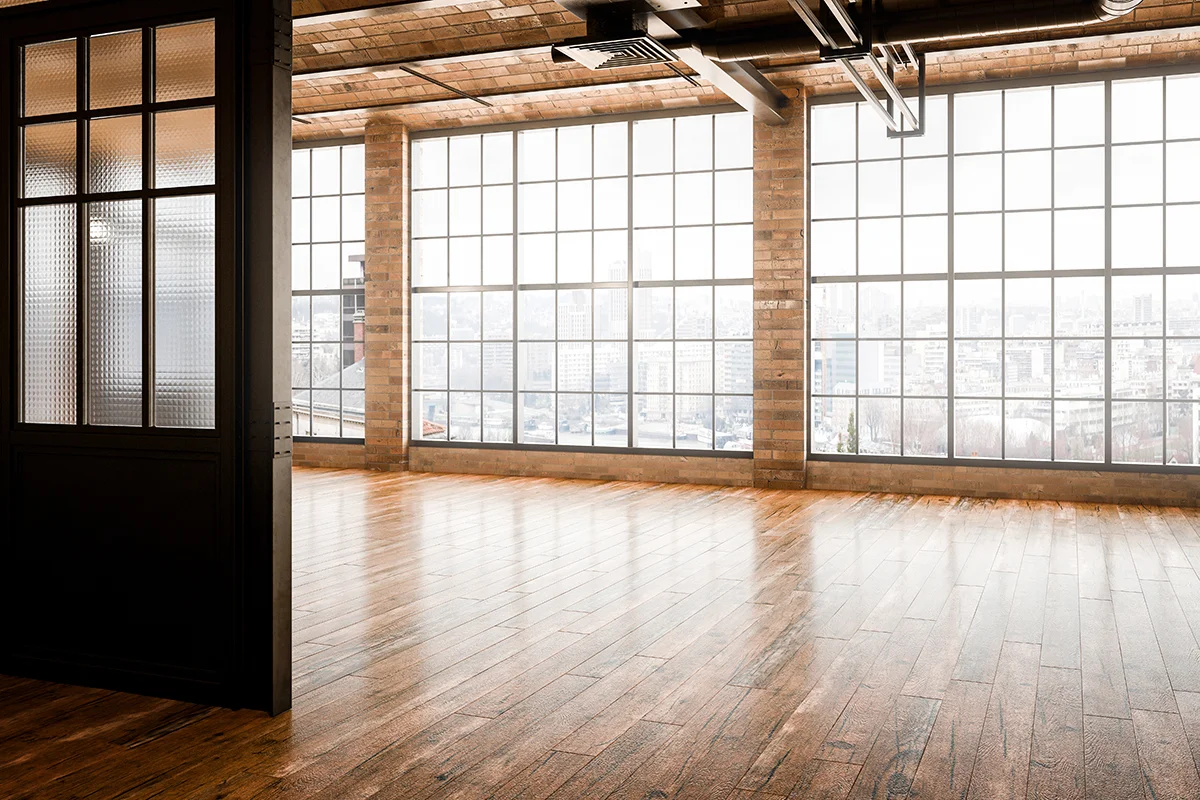 The interior of a modern commercial building after a commercial remodeling project, with brick walls, large windows, and hardwood floors